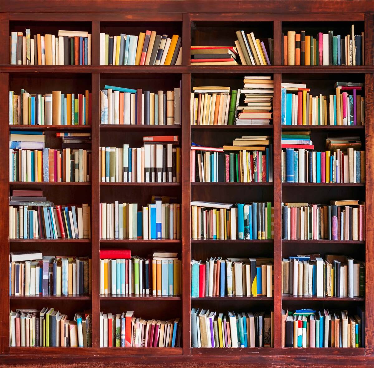 Fotobehang rijen boeken in verschillende kleuren op de planken