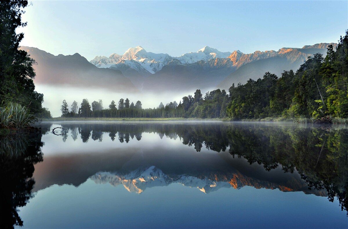Fotobehang de top van een bergmeer is in mist gehuld