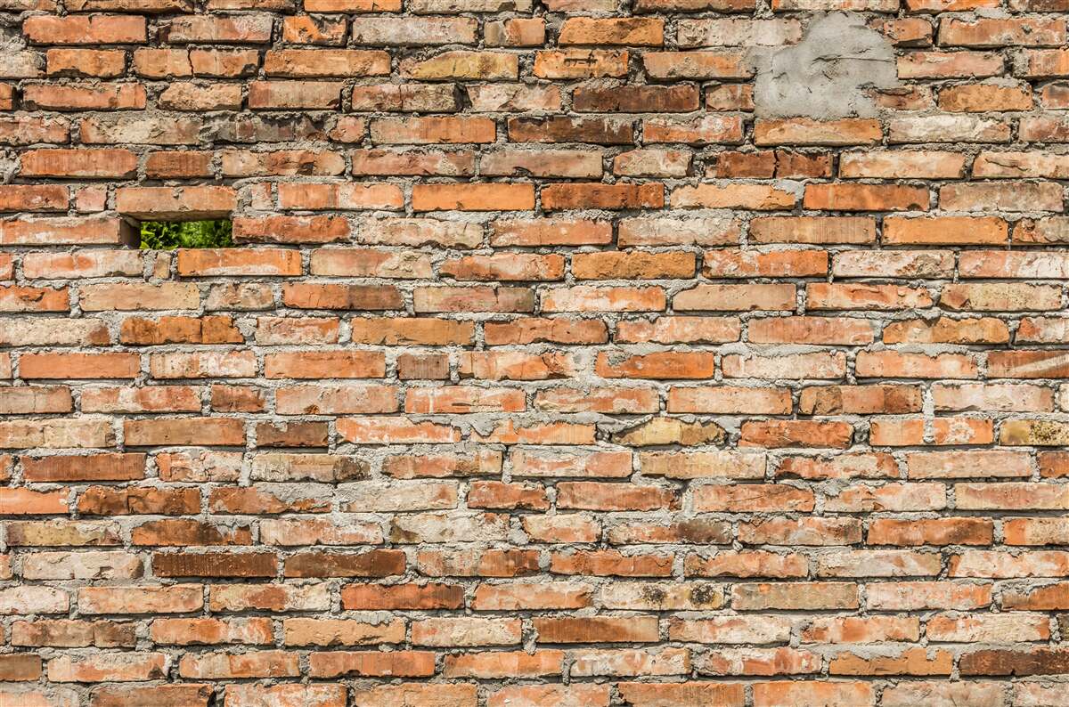 Fotobehang Een muur met vallende stenen die hun frisheid hebben verloren
