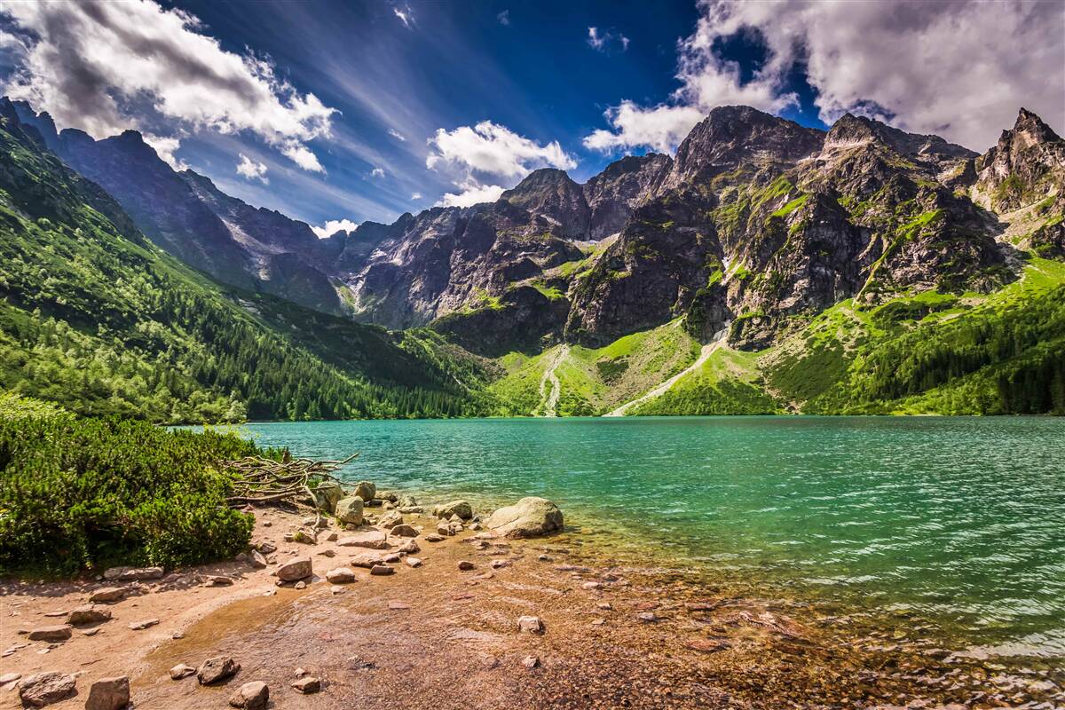 Fotobehang een zomerse dag bij een meer omringd door groene bergen