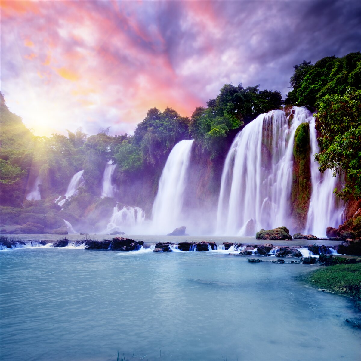 Fotobehang een enorme waterval op een achtergrond van een zonsondergang