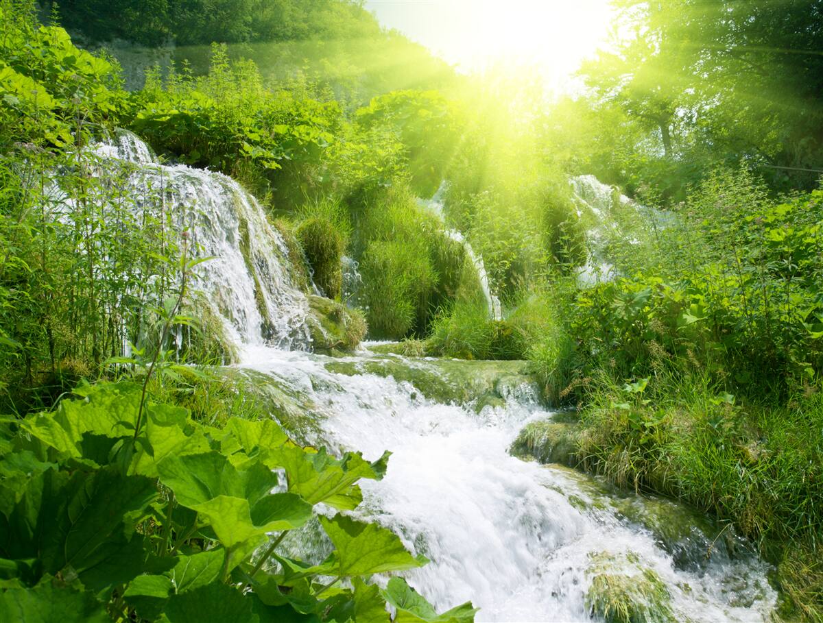 Fotobehang een verblindende zon verlicht een schuimende waterval
