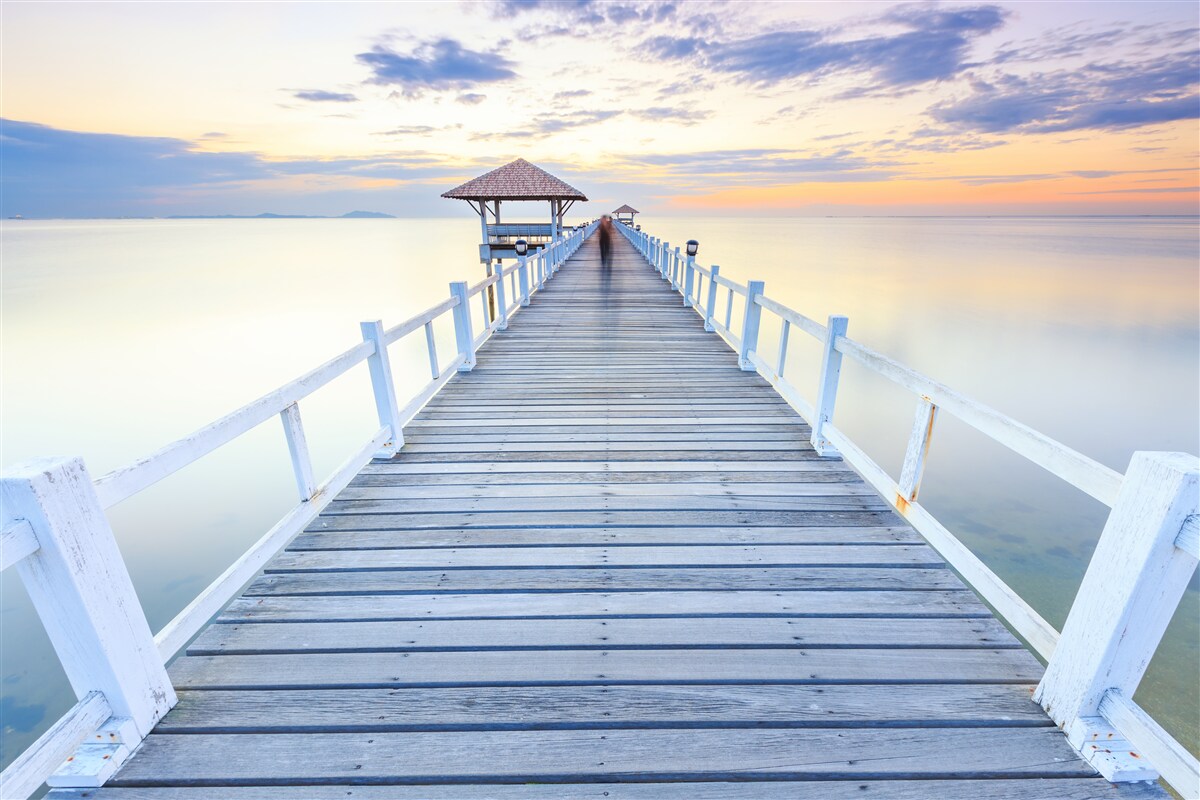 Fotobehang pier met een gazebo over het water bij zonsopgang, waar menigeen