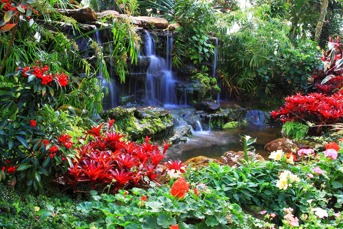 Fotobehang een magische plek bij een waterval, omringd door bloemen